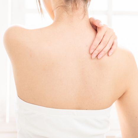 肩に天然ハーブ軟膏を塗り込む女性